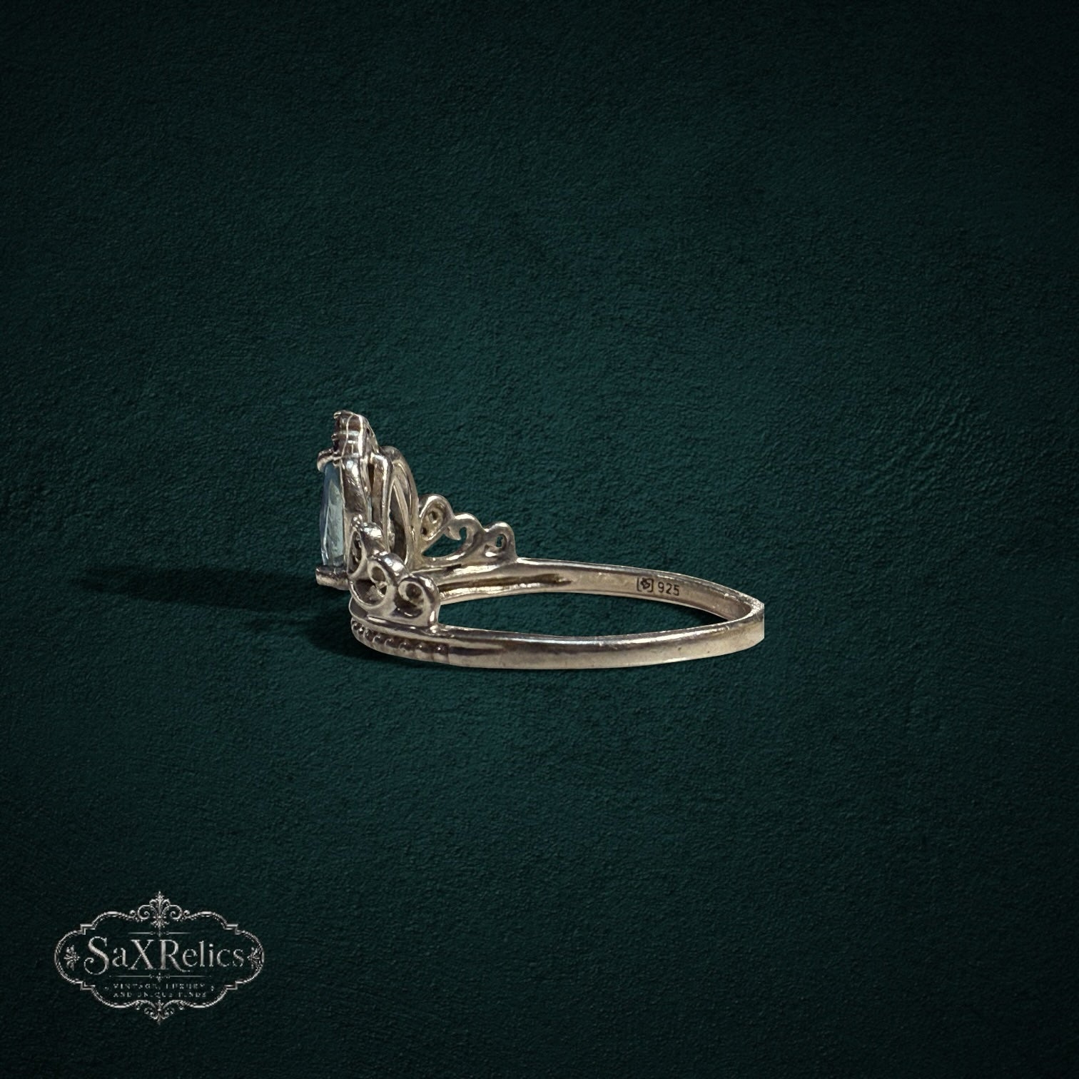 My Store SAXRelics sterling silver tiara ring with a pear-cut light blue gemstone and intricate crown filigree detail