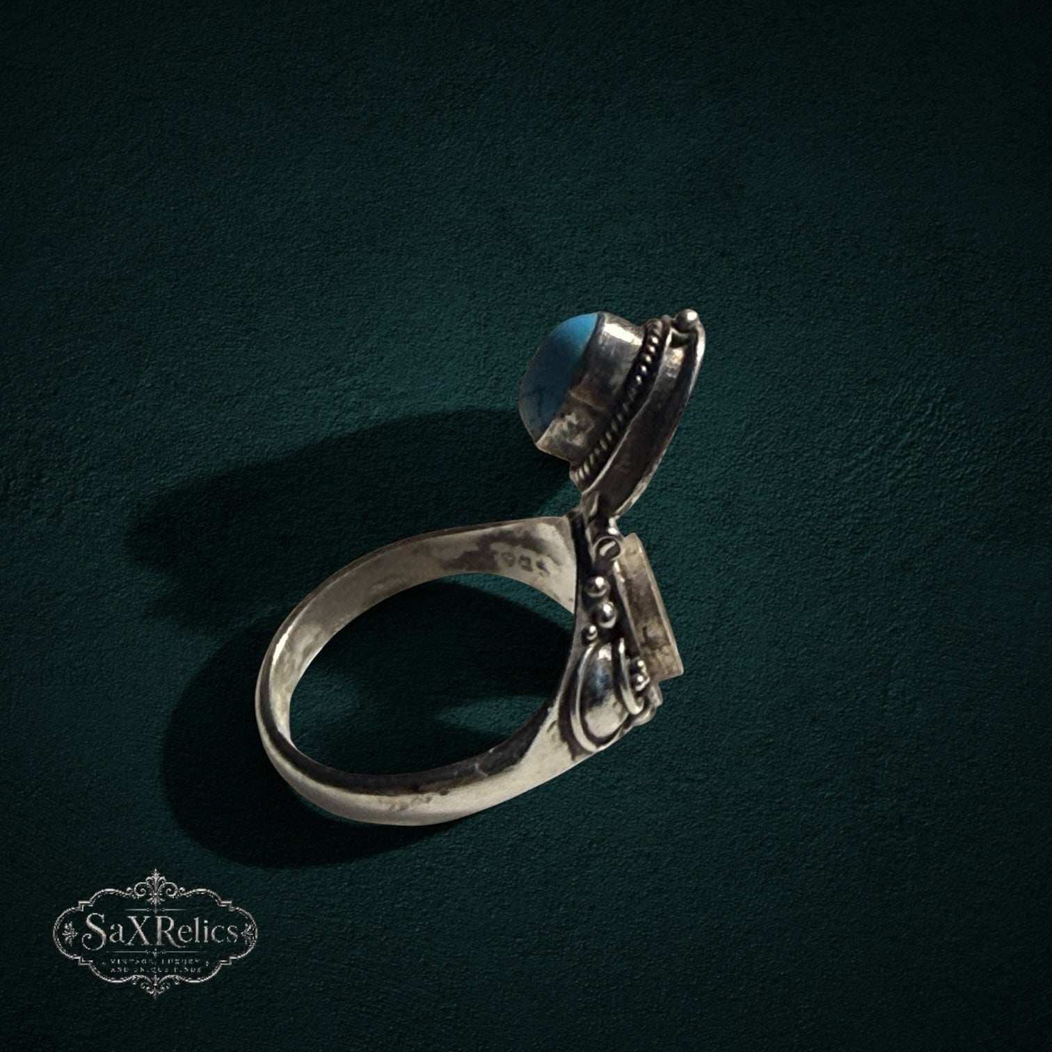 My Store vintage style sterling silver poison ring with a hinged turquoise stone lid and intricate scrollwork detail.