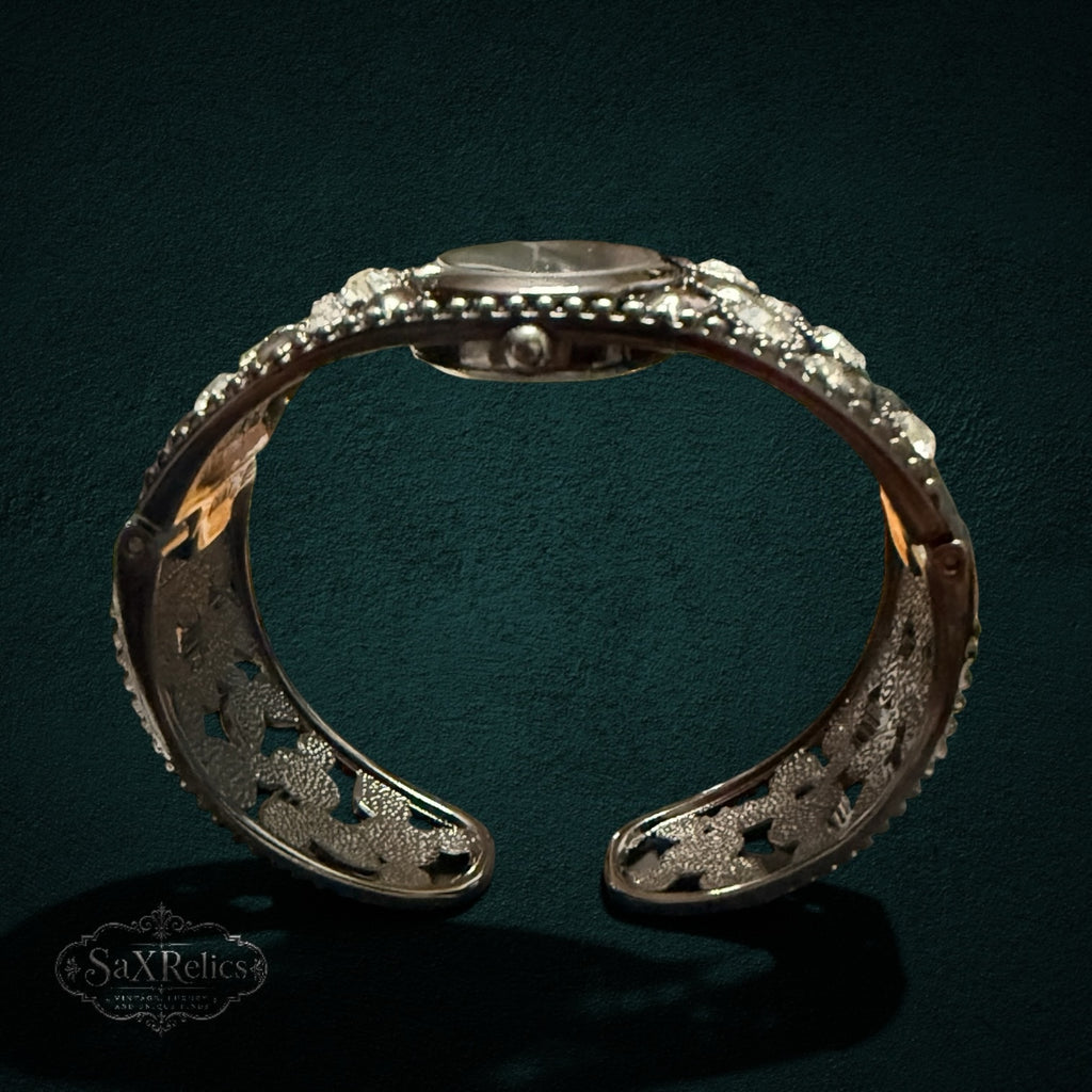 My Store STUDIO cuff watch in gunmetal with an ornate open-work band and crystal accents on a dark background.