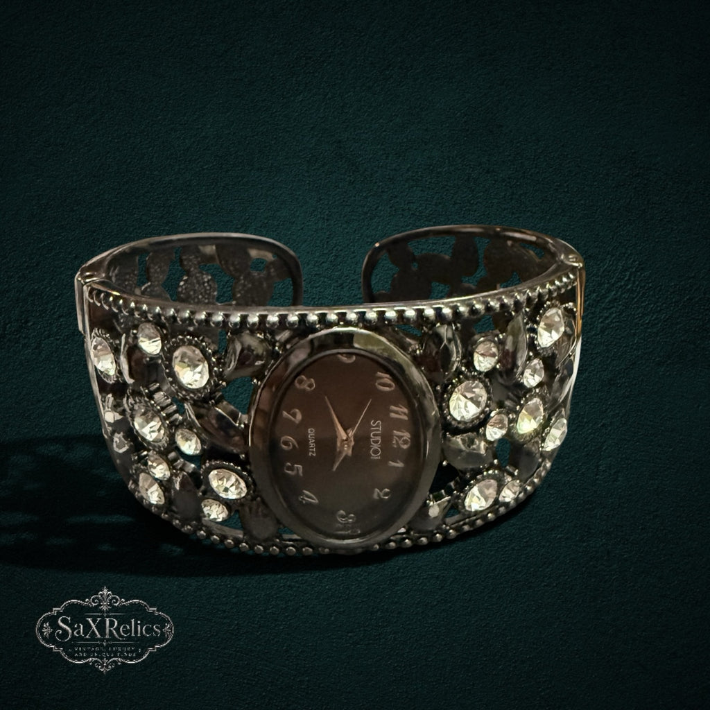 My Store STUDIO gunmetal cuff watch with an oval dial and intricate crystal-embellished open-work metal band.