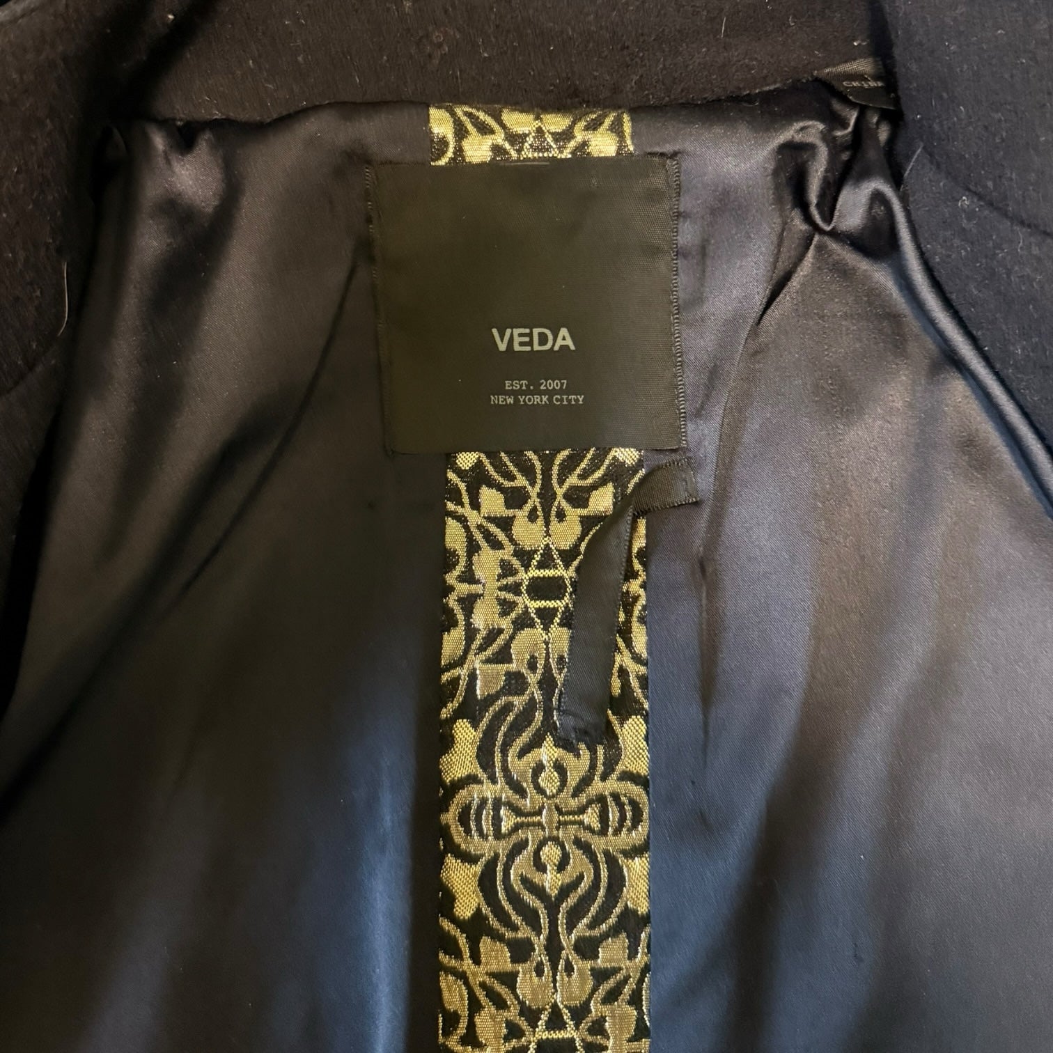 My Store VEDA jacket interior featuring black lining and intricate gold-toned brocade detail on the brand label