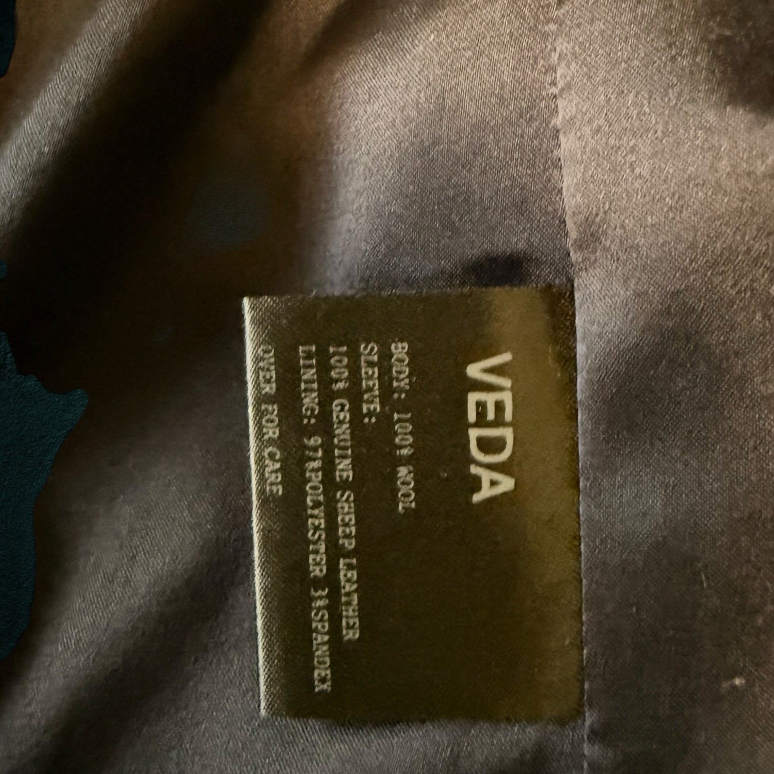 My Store VEDA jacket interior label showing 100% wool body, genuine sheep leather sleeves, and polyester lining.