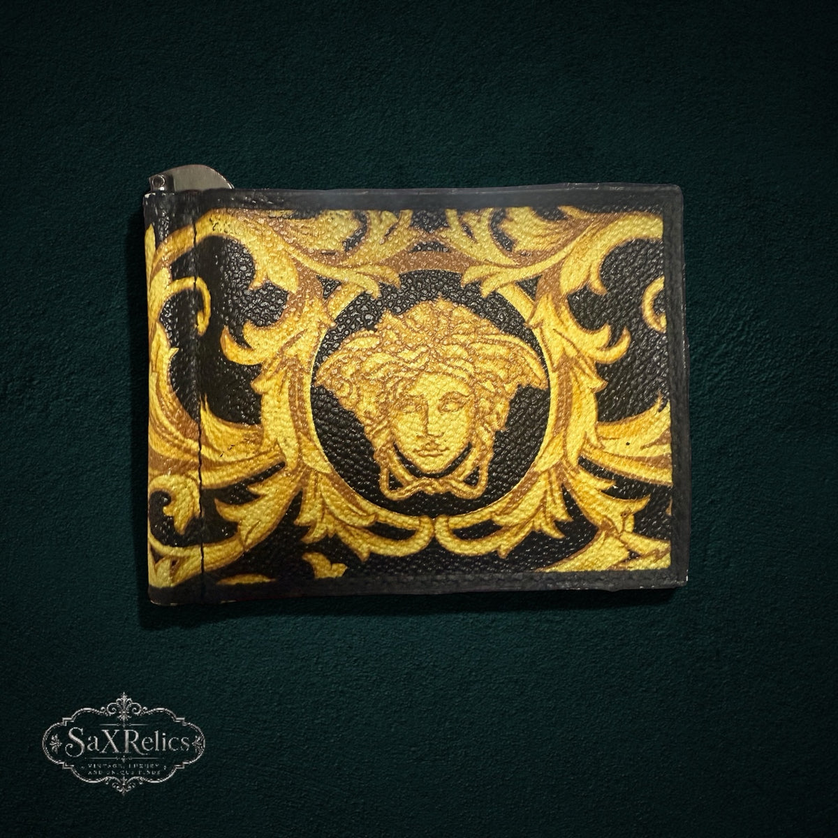 My Store Versace black leather money clip wallet featuring a gold-tone baroque print and iconic Medusa head emblem.