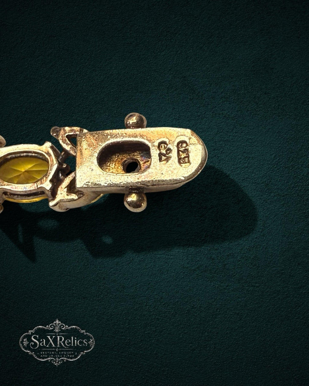 My Store vintage SAXRelics bracelet clasp showing metal hallmark and yellow gemstone link on dark green background