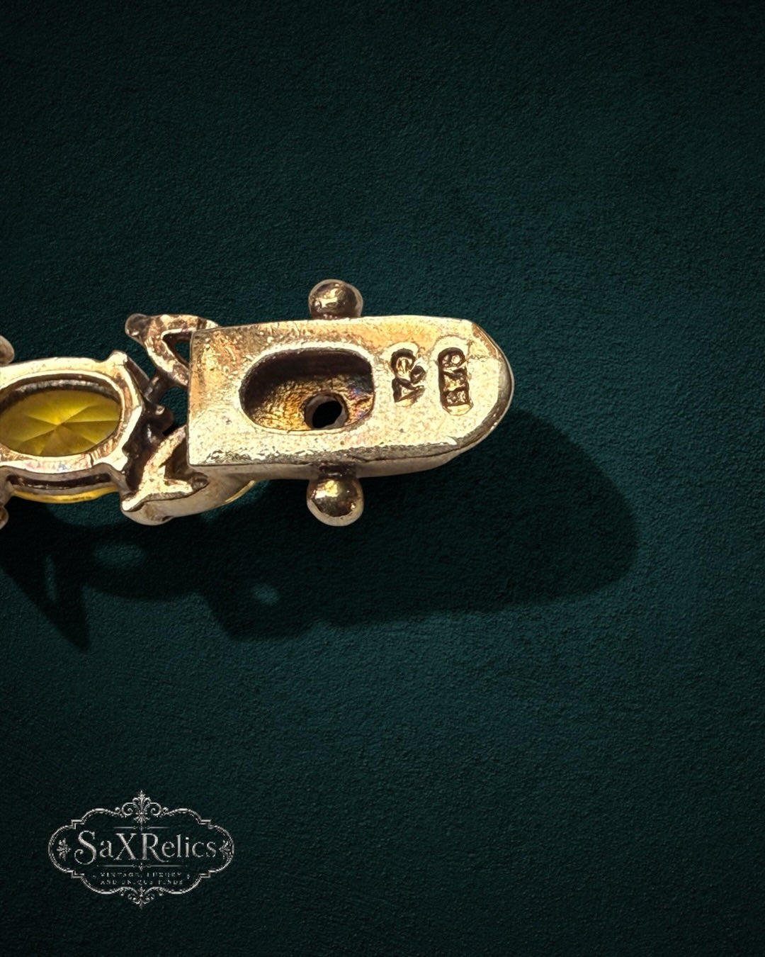 My Store vintage SAXRelics bracelet clasp showing metal hallmark and yellow gemstone link on dark green background