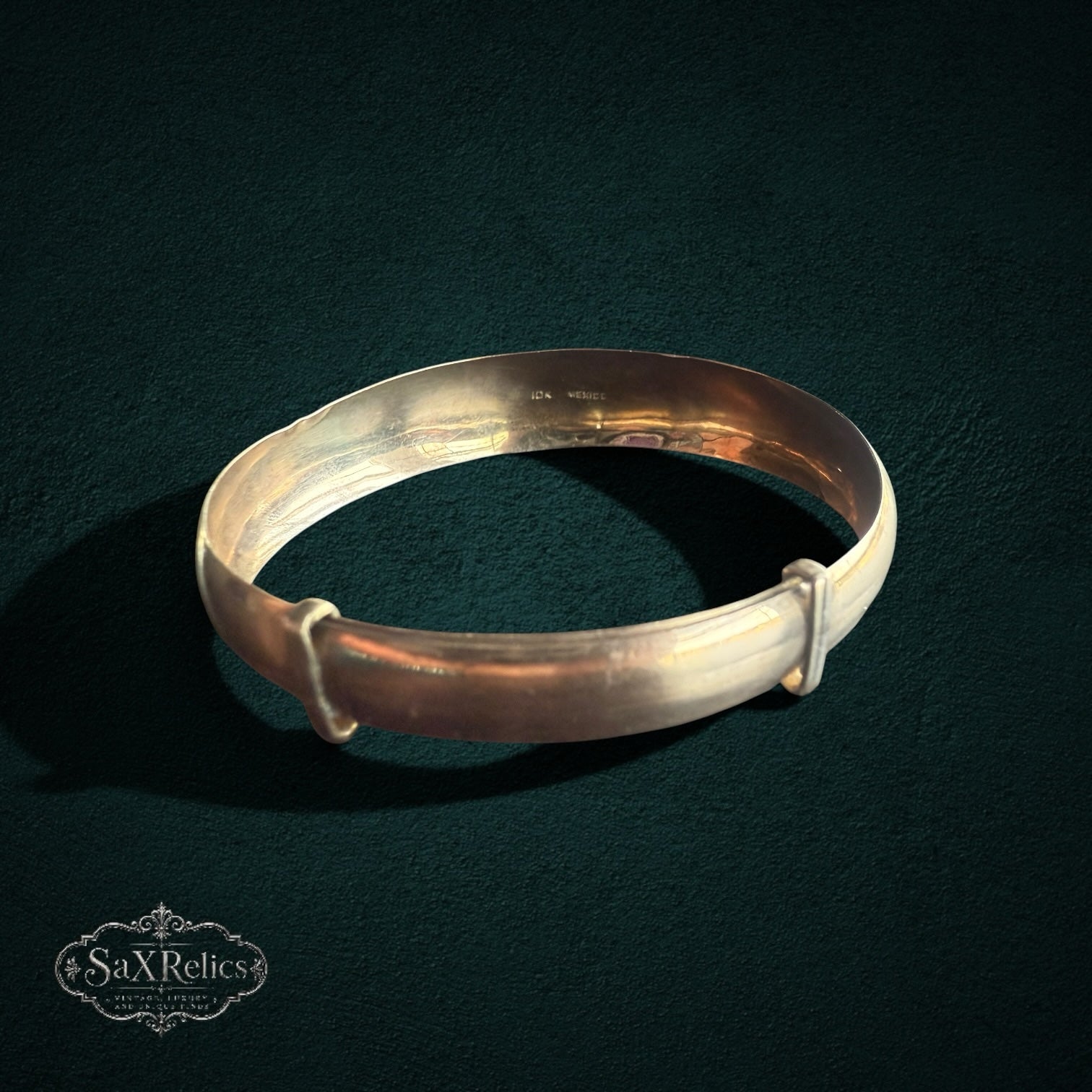 My Store vintage-inspired gold expandable bangle bracelet with a smooth, polished finish on a dark background.