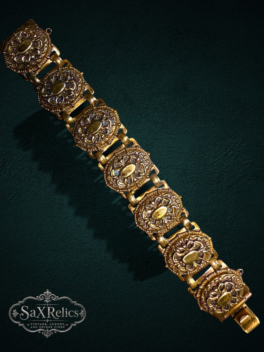 Vintage-inspired gold-tone link bracelet featuring ornate oval filigree and scrollwork patterns.