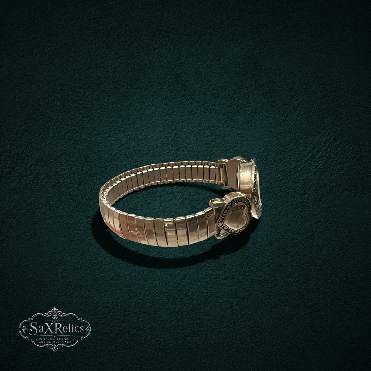 My Store vintage-inspired gold-tone quartz watch with heart accents and a flexible expansion band on a dark background.