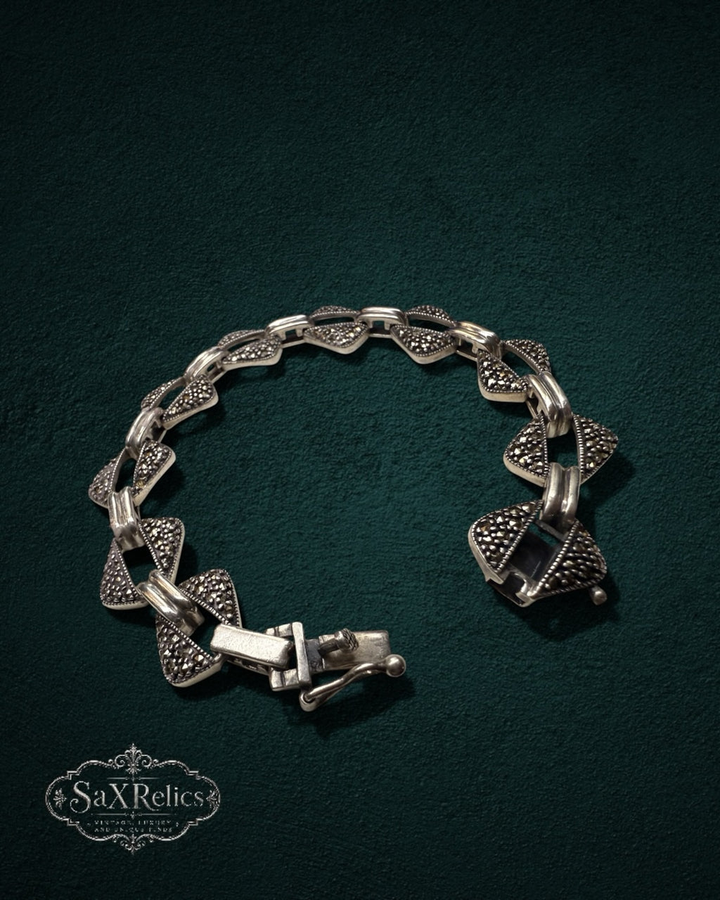 My Store vintage sterling silver geometric link bracelet with triangular marcasite pavé stones on a dark green surface.