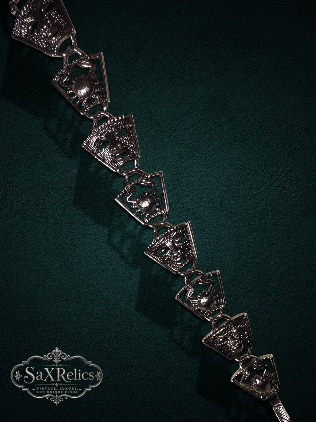 Vintage silver-tone link bracelet featuring alternating theatrical mask and crab motifs on a dark background.