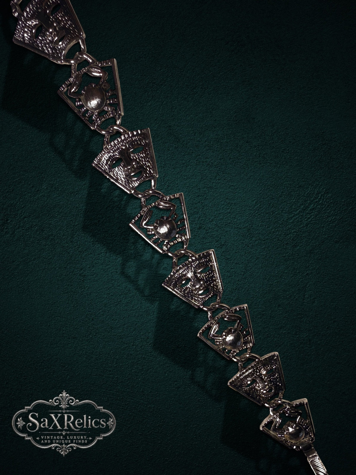 Vintage silver-tone link bracelet featuring alternating theatrical mask and crab motifs on a dark background.
