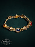 Vintage gold-tone link bracelet featuring multi-colored cabochon stones and crystal-accented diamond links.