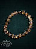 My Store vintage-inspired gold-tone link bracelet featuring iridescent cabochon faux opal stones on a dark background.