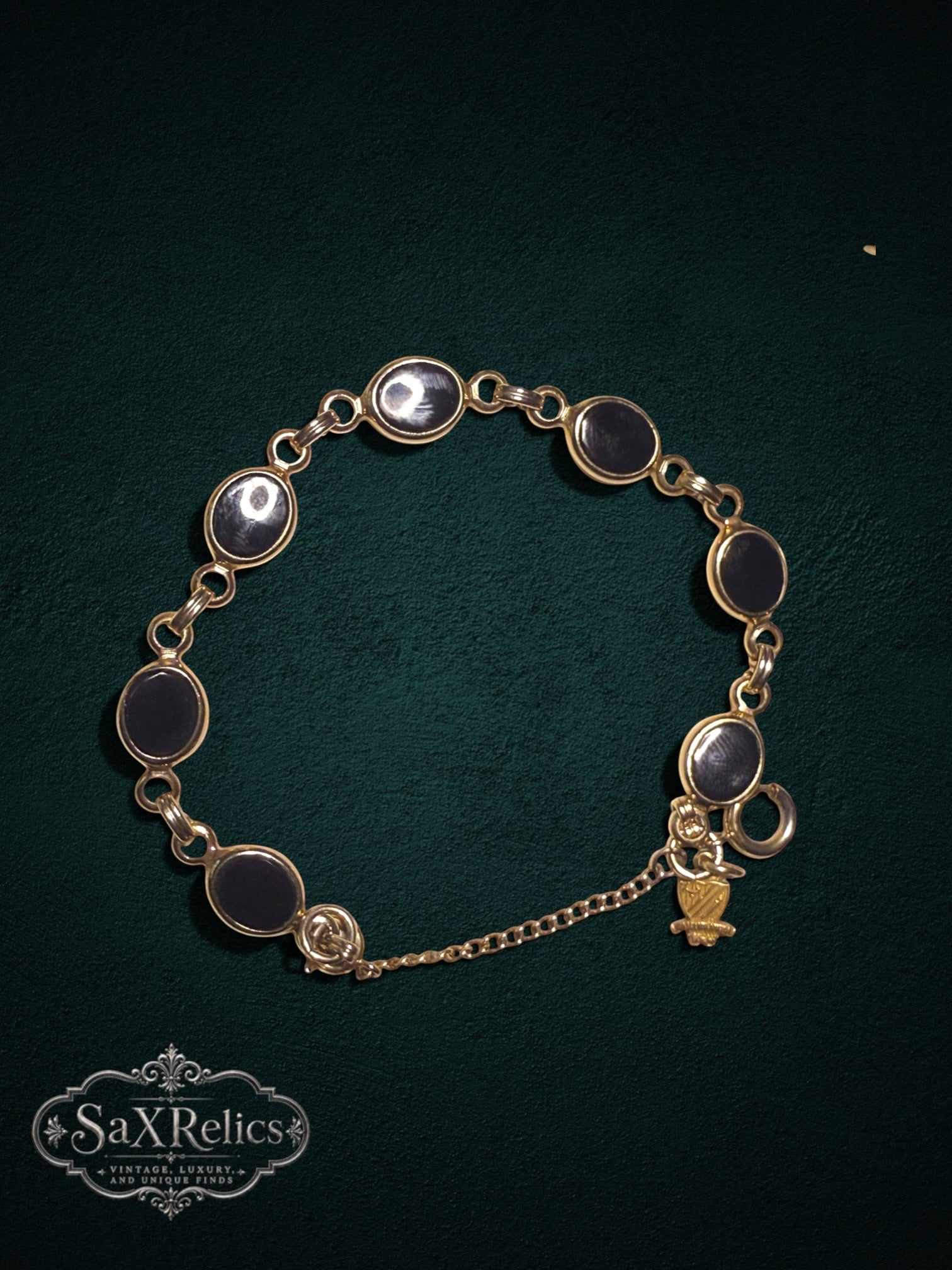 My Store vintage gold-tone bracelet featuring oval black cabochon links and a detailed heraldic crest charm.