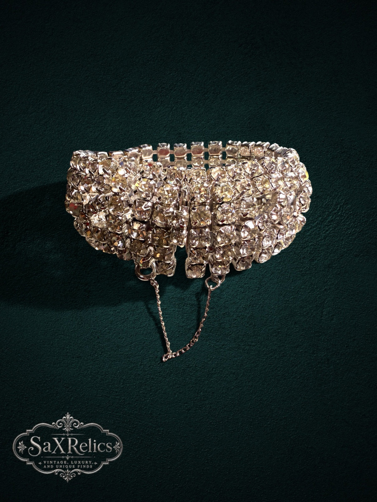 Vintage rhinestone wide cuff bracelet with clear crystals and silver-tone metal on a dark green background