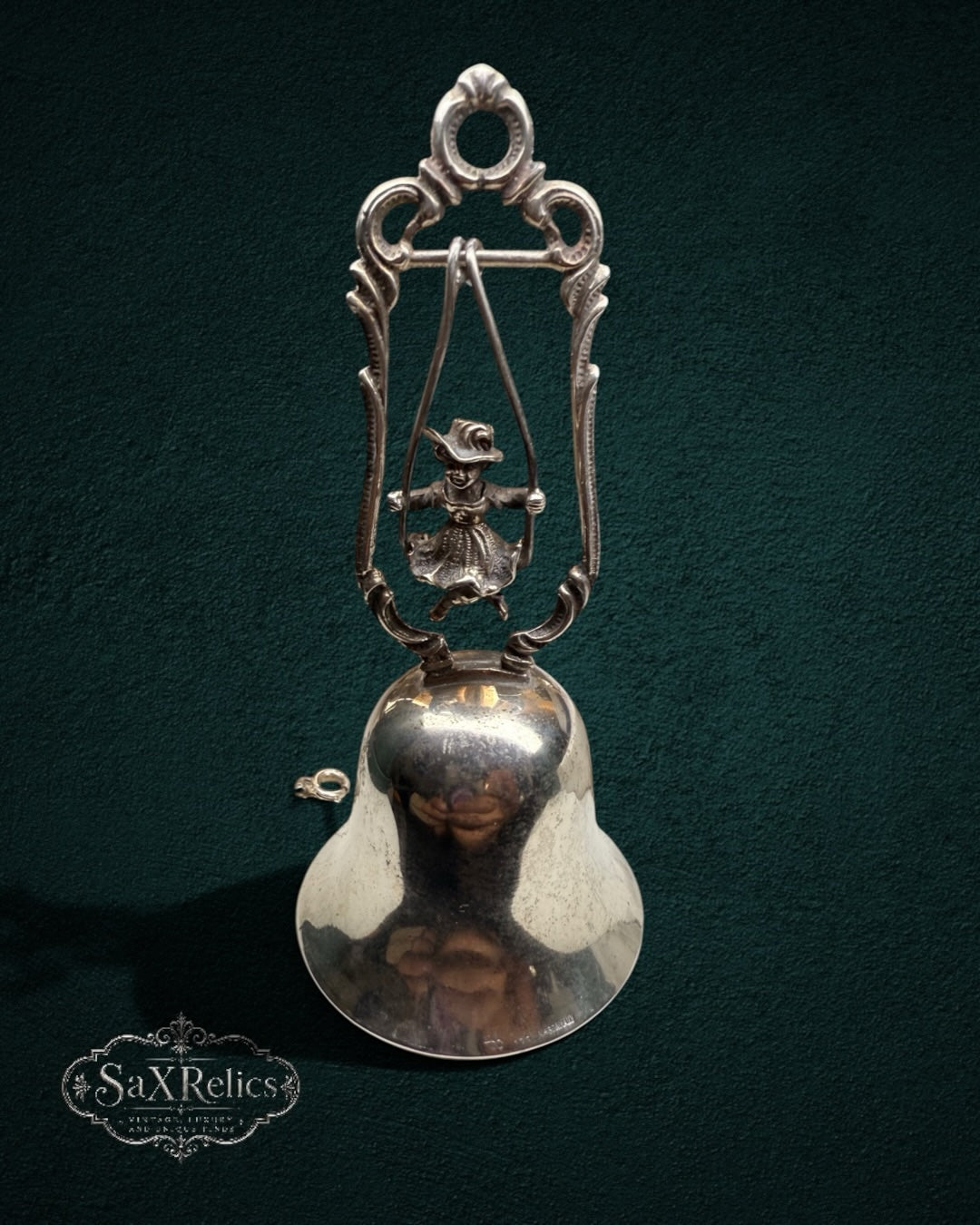 My Store vintage silver-plated table bell featuring a child on a swing inside an ornate scroll-work frame.