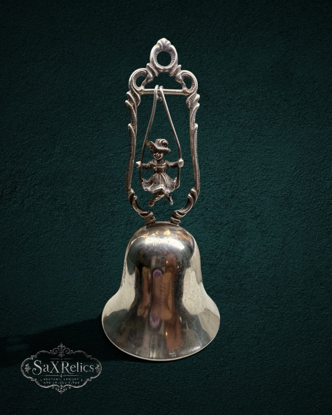 My Store vintage silver-plated table bell featuring a child on a swing inside an ornate scroll-work frame.