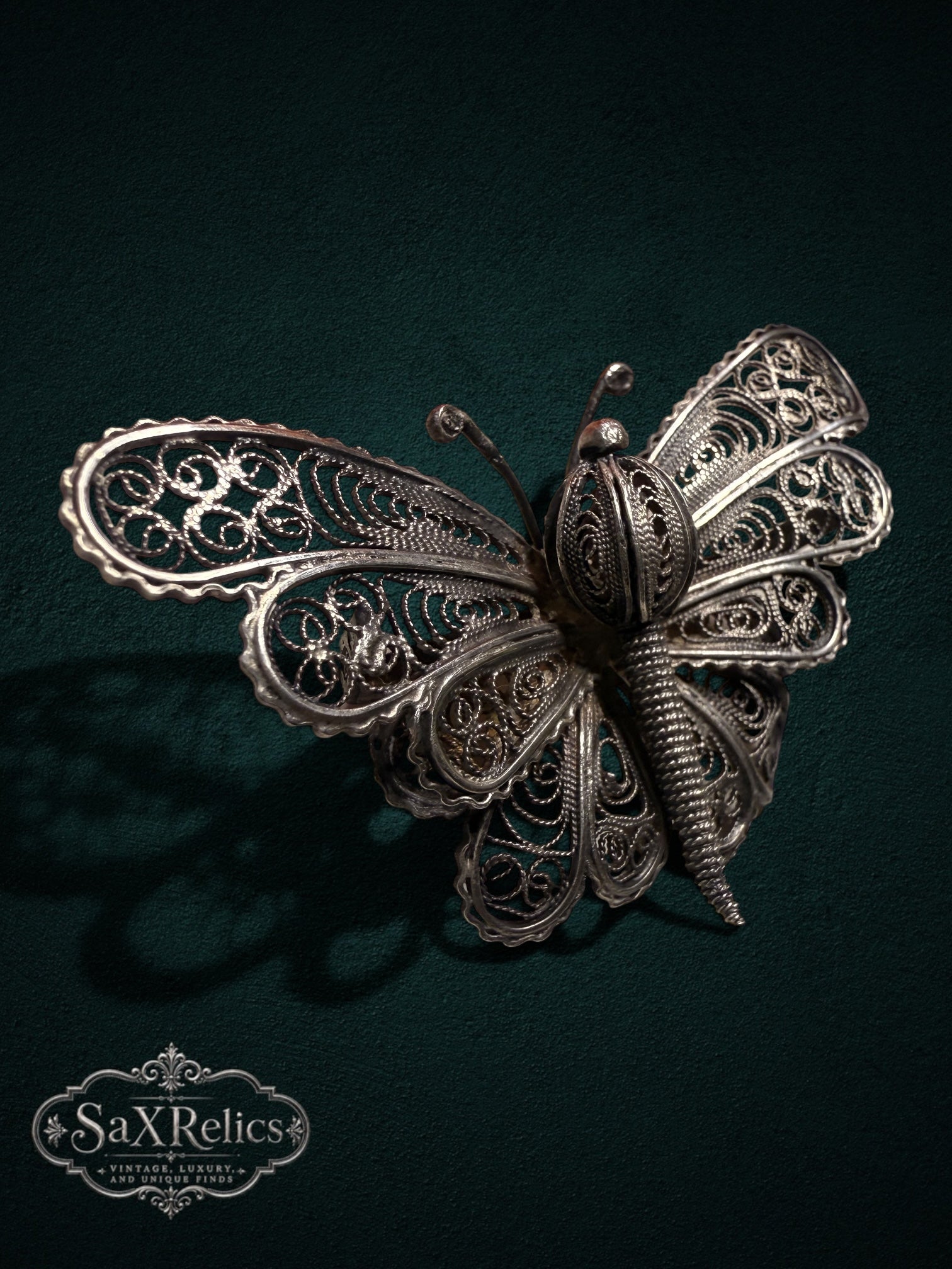 My Store vintage silver filigree butterfly brooch featuring intricate wirework patterns on a dark green background