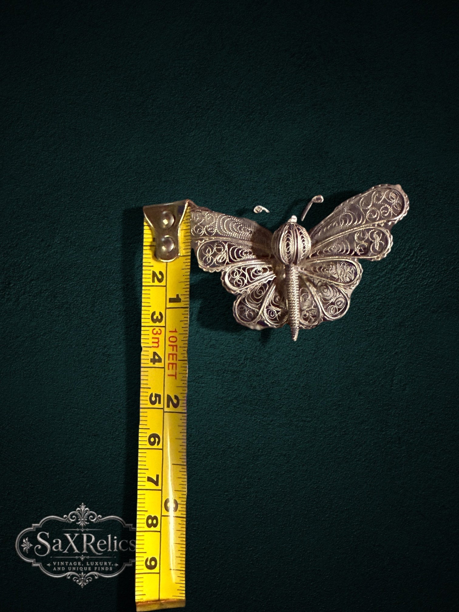 My Store vintage silver filigree butterfly brooch with intricate wirework patterns measured against a yellow tape.