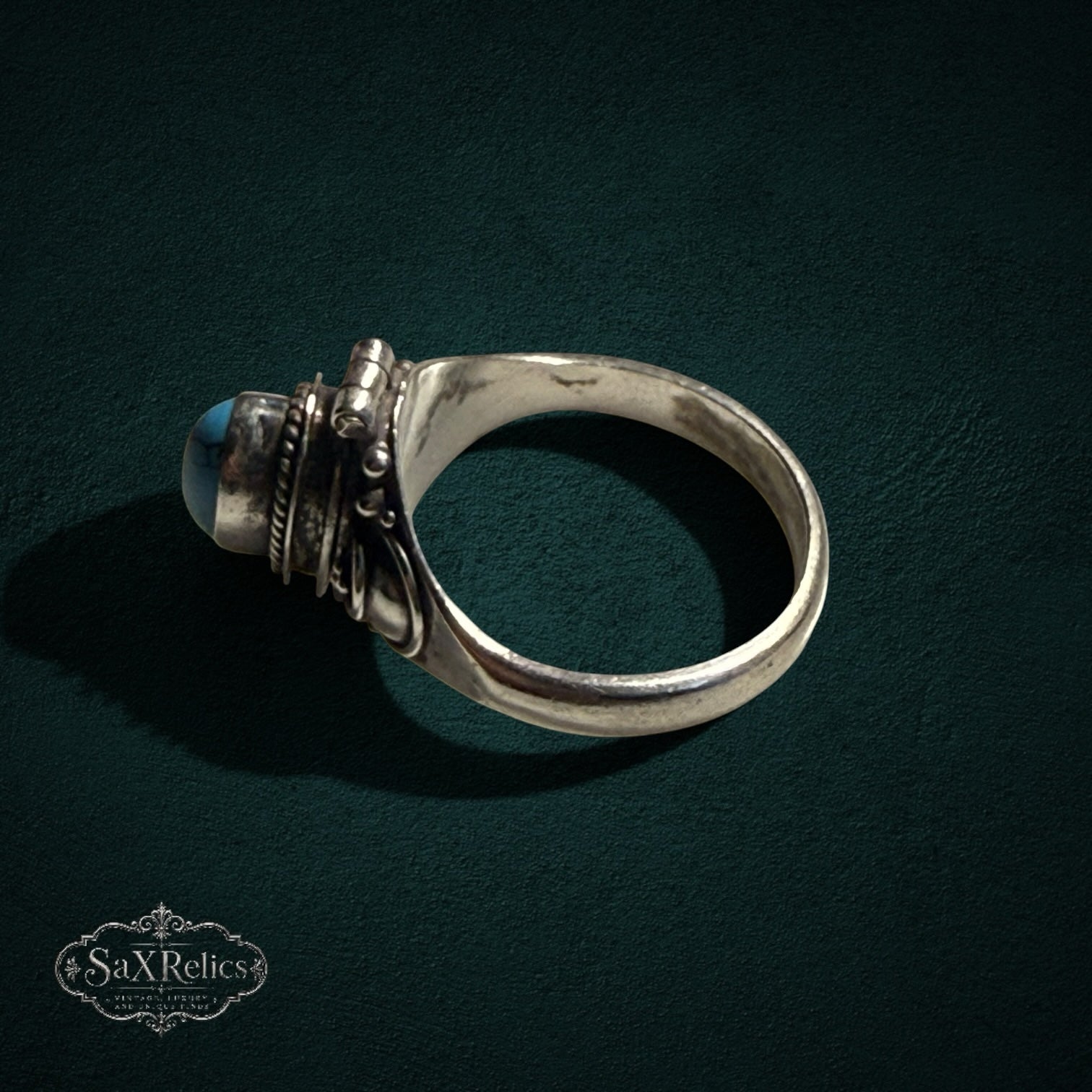 My Store SAXRelics vintage sterling silver poison ring with a hinged turquoise stone and intricate scrollwork band.