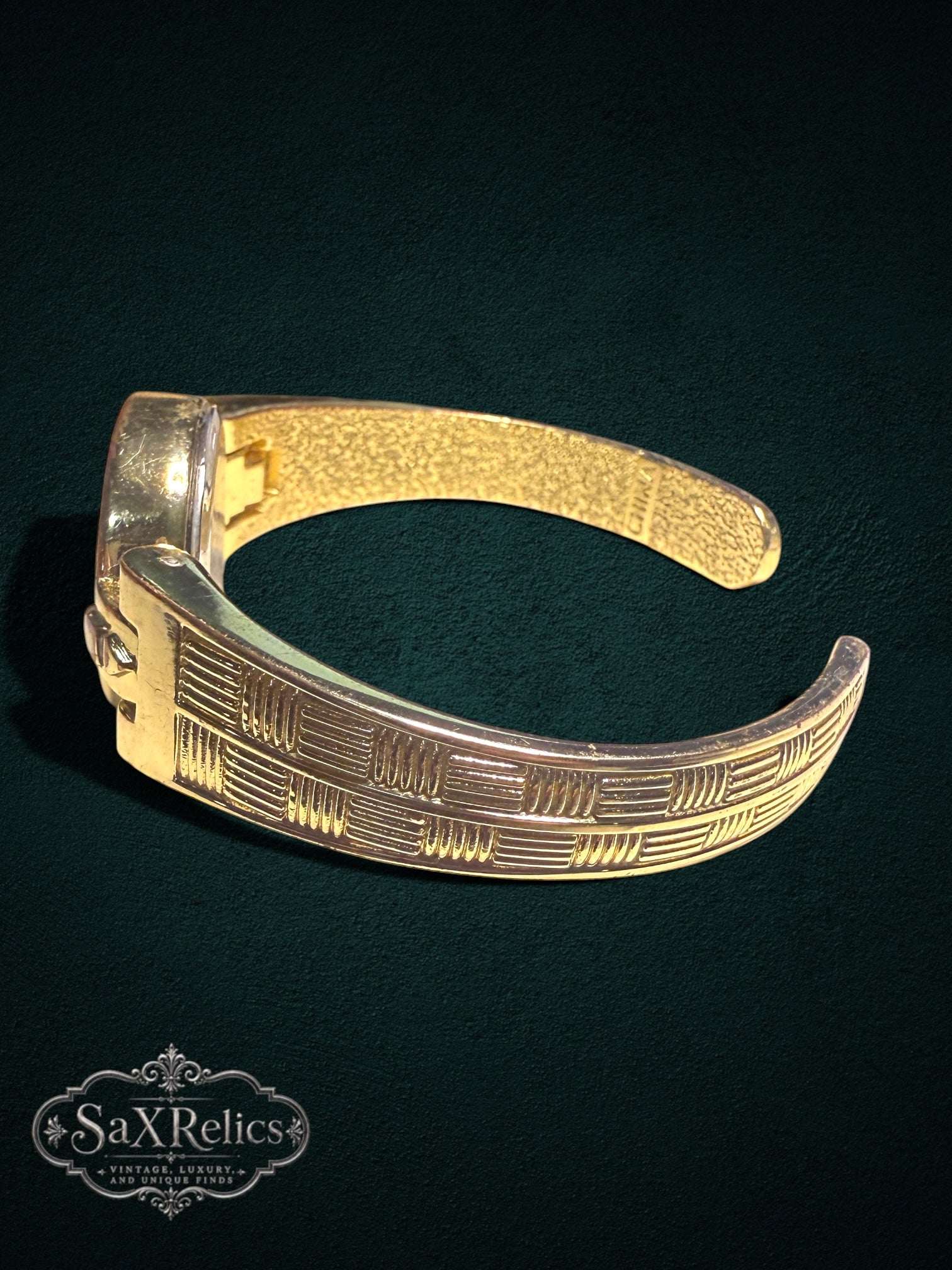 My Store Vivani gold-tone cuff watch with textured geometric band and open-cuff design on a dark background.